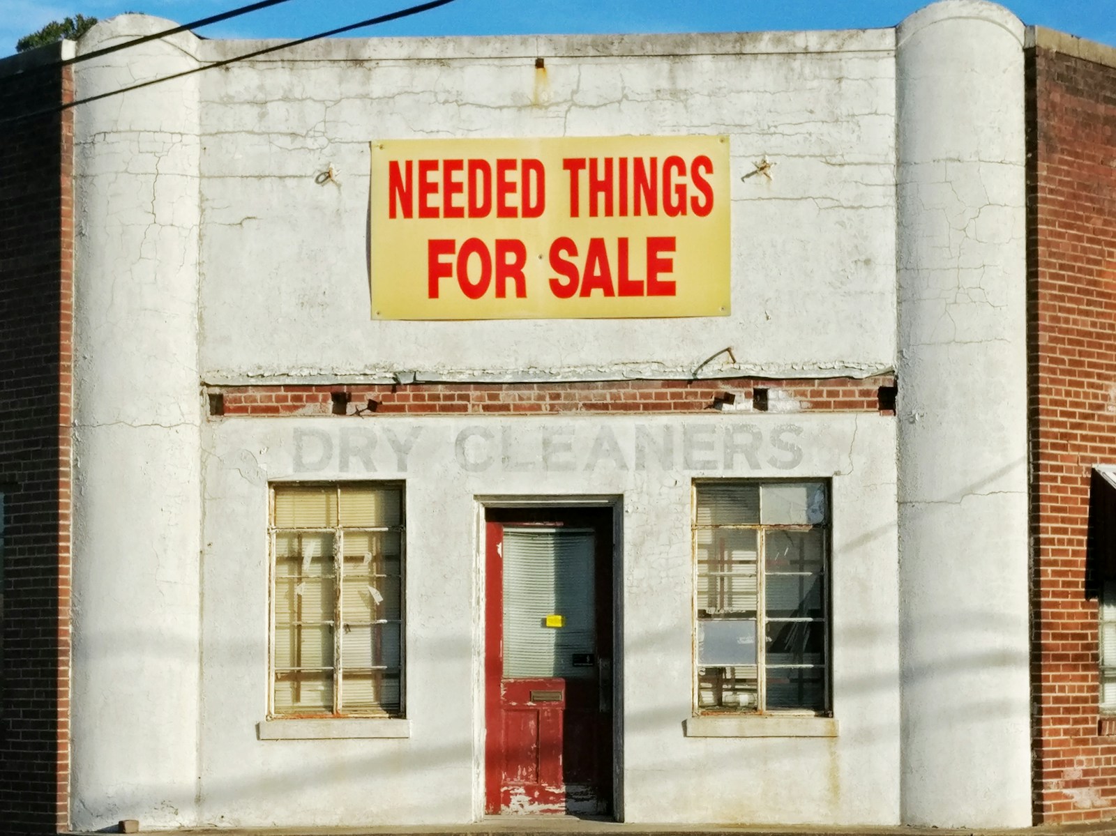 Photo by Michael Prewett needed things for sale poster posted on white concrete establishment